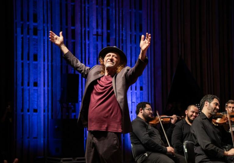 Alceu Valenca on stage with his arms in the air 