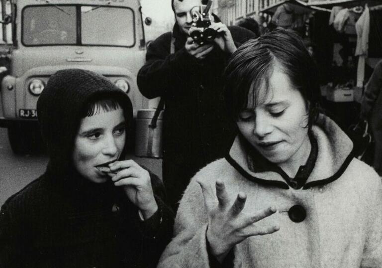 Two children eat biscuits on a street in an old photography from mid-20th Century.