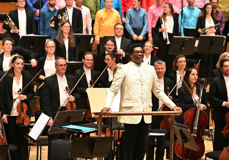 Conductor Andre J Thomas takes his bow on the Barbican stage with the London Symphony Orchestra and LSO Community Gospel Choir