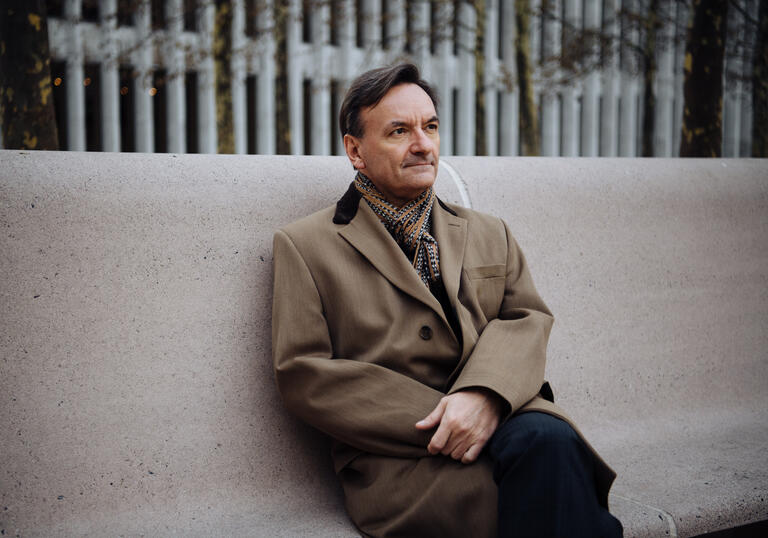 Stephen Hough sitting on a concrete bench