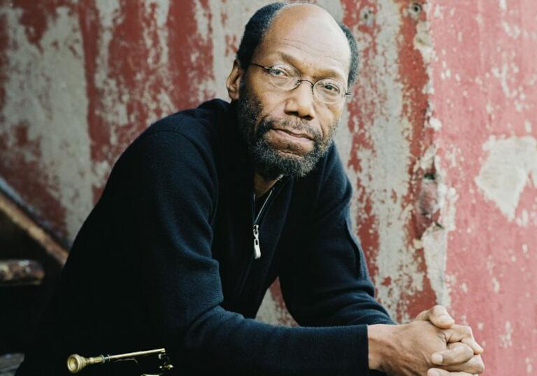 Charles Tolliver looks to camera, sitting on stairs