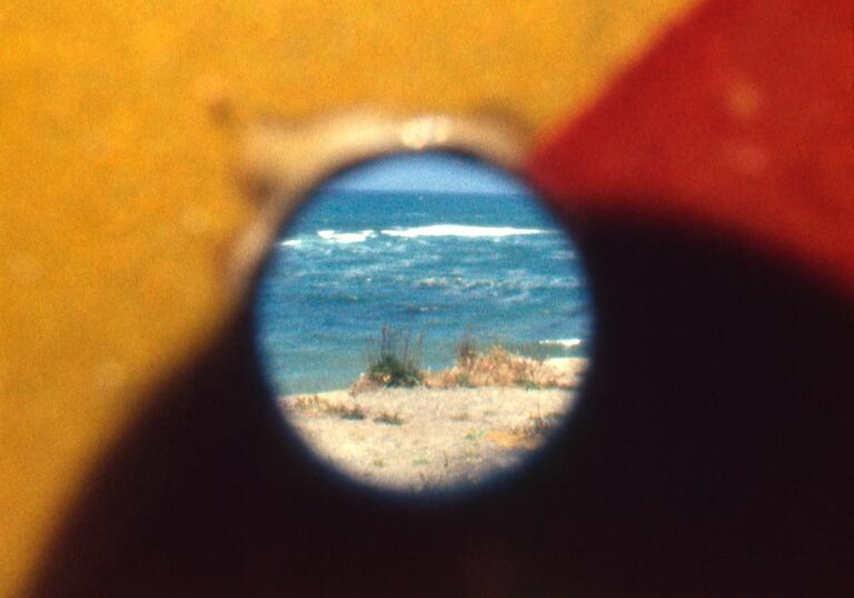 A yellow and red hole shows a beach scene.