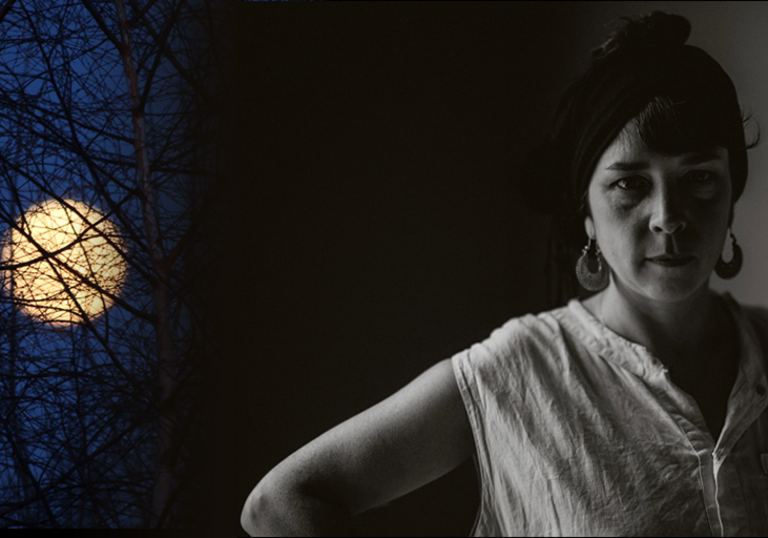 Lisa O'Neill looks to camera with hand on her hip, with the cold moon looming above here