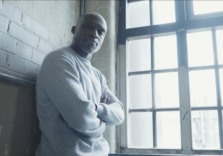 Image of man leaning against wall by a window