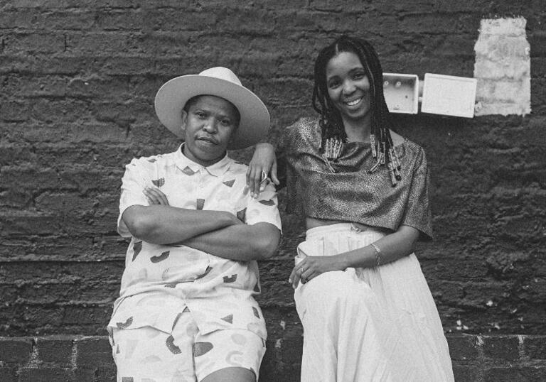 Siya and Thandi leaning against a brick wall