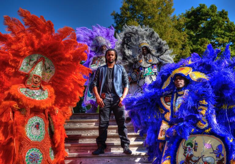Bo Ellis stands surrounded Mardi Gras performers