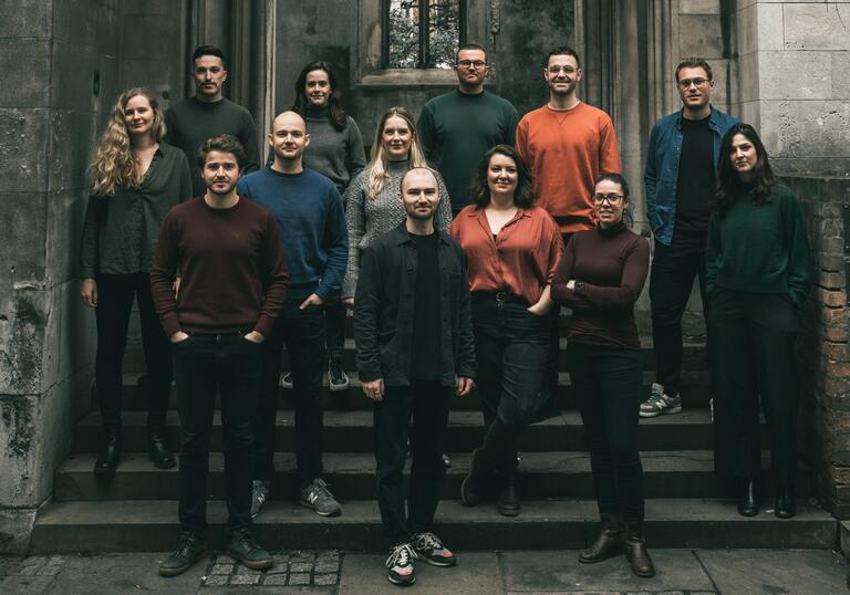 Sansara Choir standing on the steps of an old, abandoned church