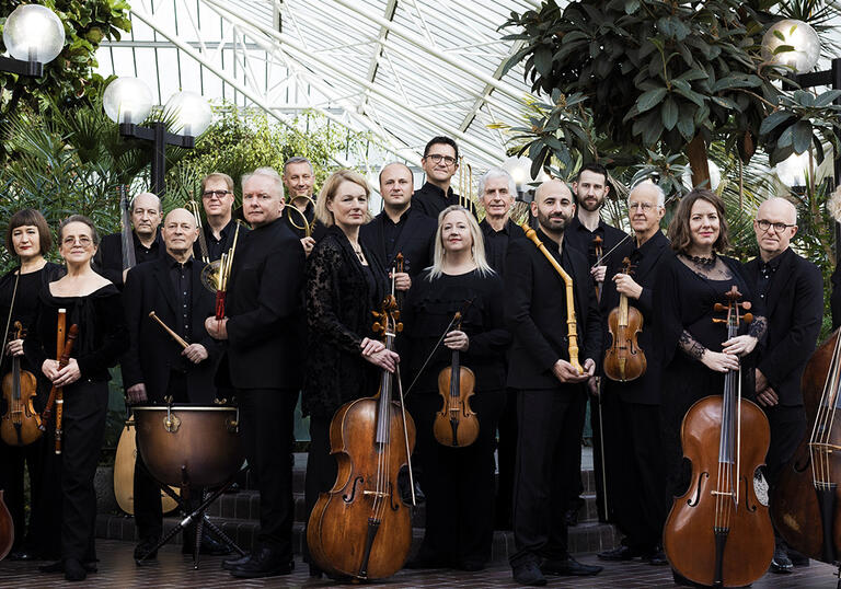 The Academy of Ancient music posing with their instruments in the Barbican Conservatory