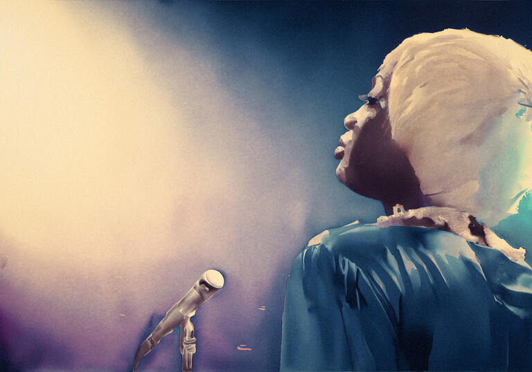 Jackie stands in profile on stage with a microphone on a stand