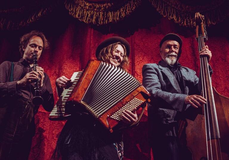 Whsikey Moonface energetically play their instruments against a red velvet curtain