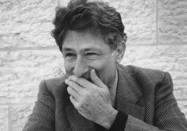 Edward Said laughs against a wall.