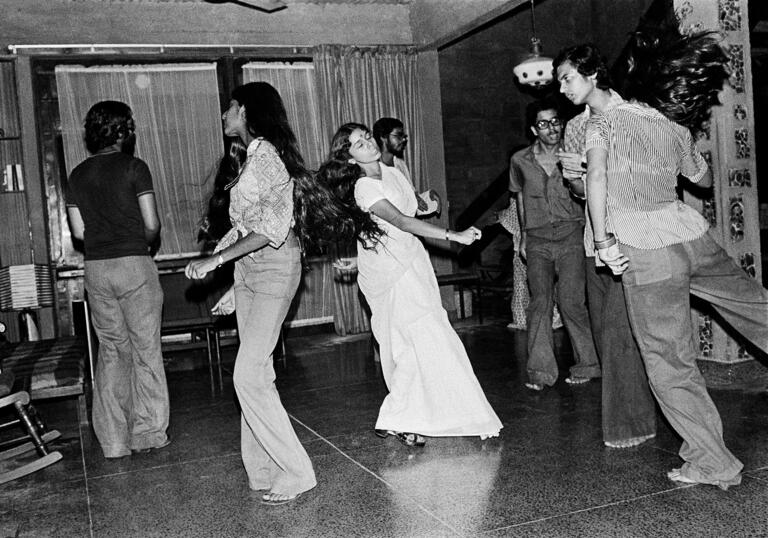 A black and white photo by Pablo Bartholomew, showing a group of people dancing at a party in New Delhi in 1975