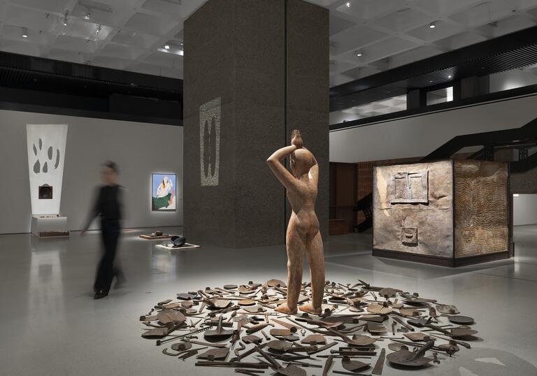 sculpture of a man surrounded by tools, in a gallery