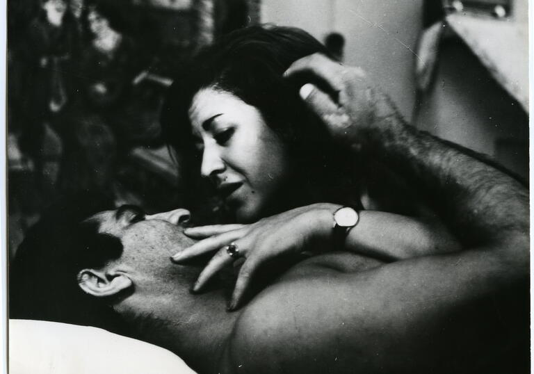 A black and white still from Brick and Mirror, showing a man and woman embracing in bed
