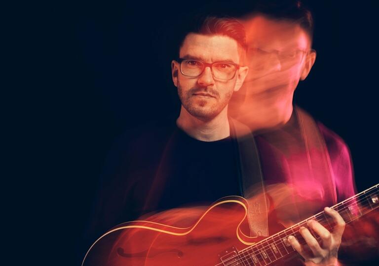 Steve Banks holding guitar in distorted image