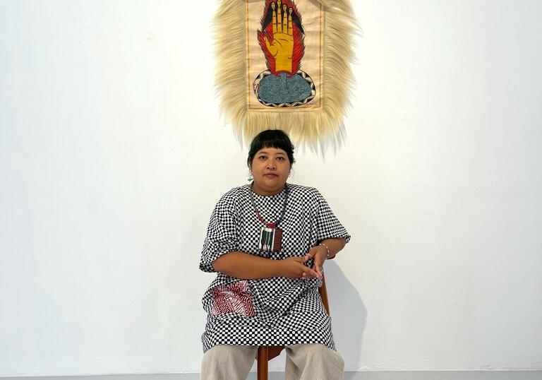 The artist sits in front of a portrait