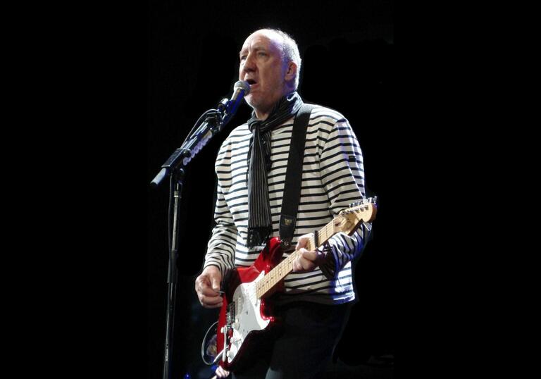 Pete Townshend playing an electric guitar in front of a microphone