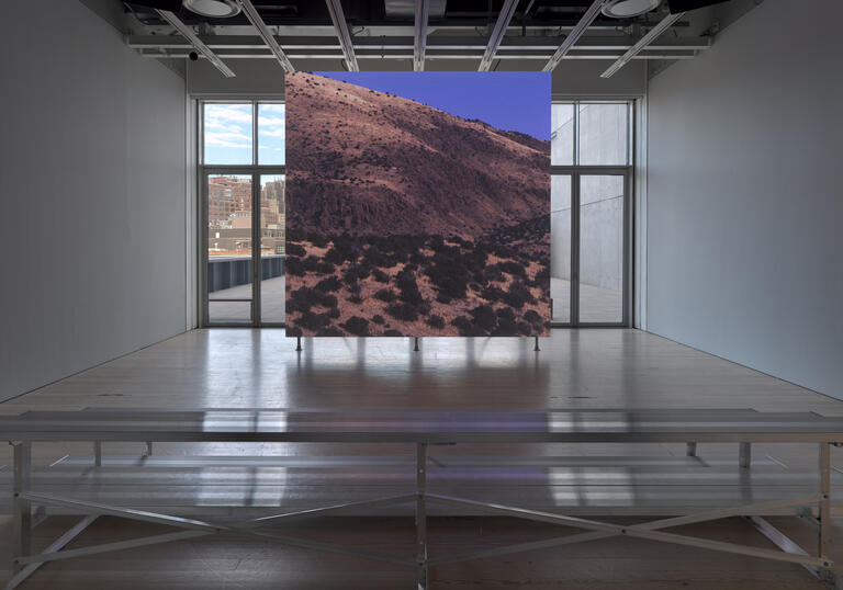 A square screen displaying a still from a video depicting a desert landscape of the American West.
