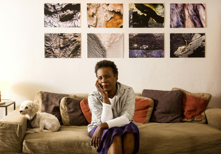 Claudia Rankine sitting on a sofa, resting her head in her hand.