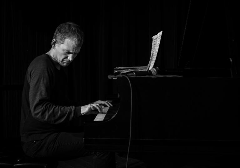 A black and white photo of pianist Brad Mehldau playing the piano