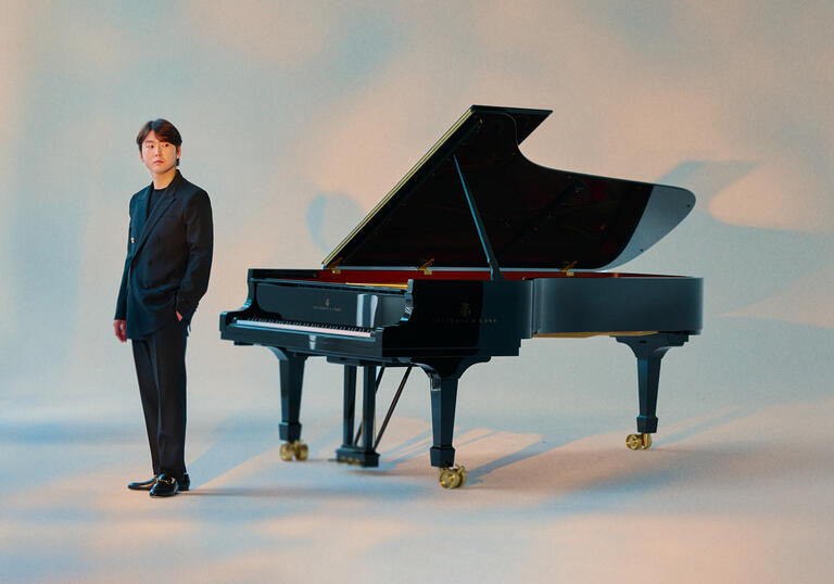 Seong-Jin Cho standing next to a piano