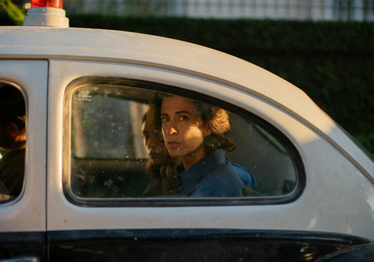 Eunice sits in the back of a police car