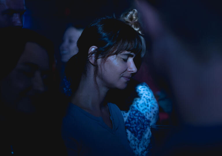 Joana Santos stands in a crowd, covered in blue light