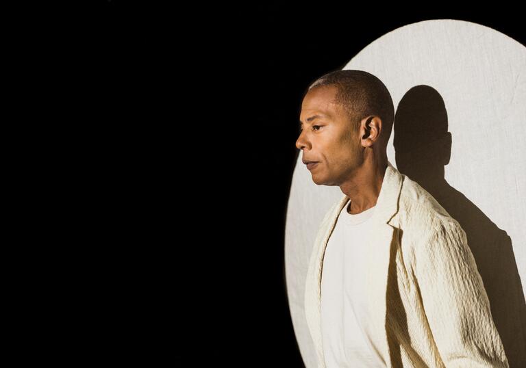Jeff Mills under a spotlight wearing a white blazer and tshirt