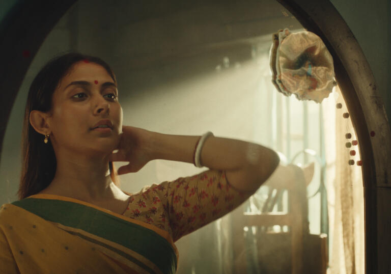 Maloti stares into a mirror, bathed in soft light