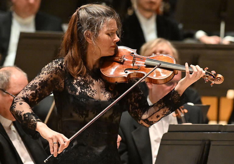 Janine Jansen on the Barbican stage, in front of the orchestra, playing the violin