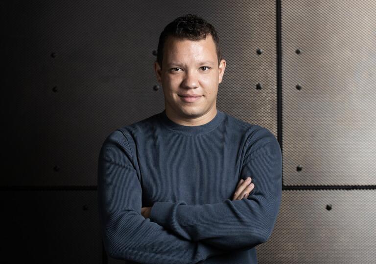 Conductor Ryan Bancroft in front of a wall looking into the camera