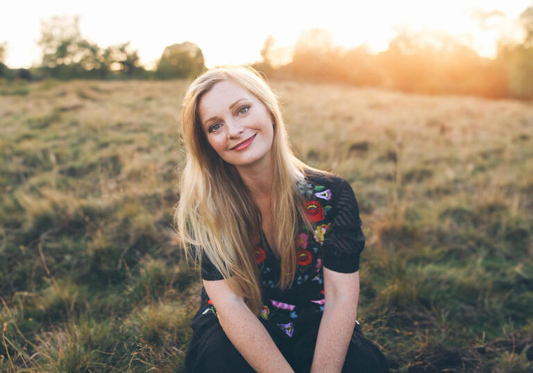 Soprano Lucy Crowe pictured in a field, with the sun setting in the background