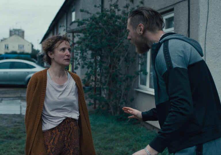 A dishevelled middle aged woman argues with a young, aggressive man