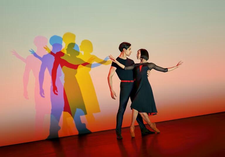 Two people dance in coloured lights.