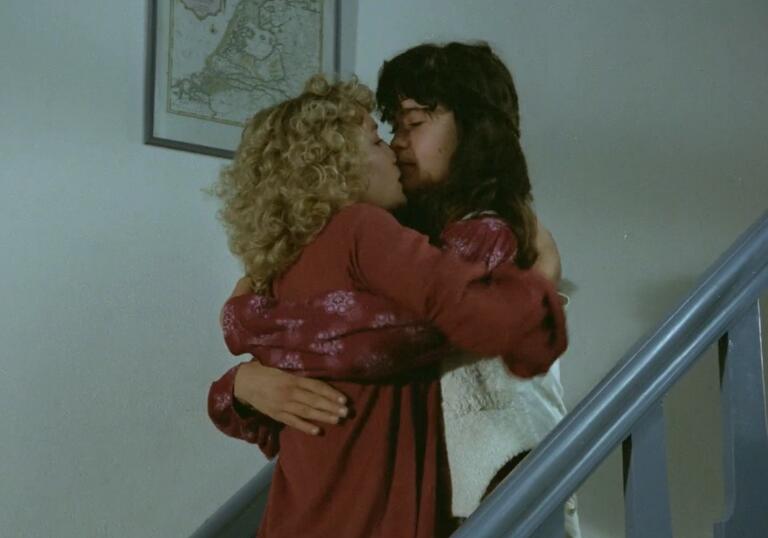 Two women embracing and kissing on a staircase