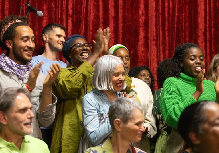 A diverse choir group smiling and clapping