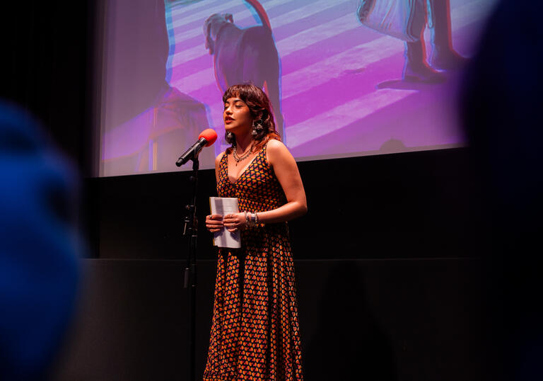 A young woman performing poetry on stage