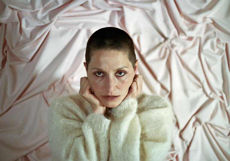 Image of Cate Le Bon with her hands on her head