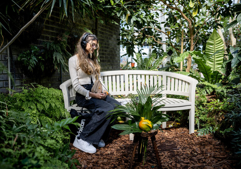 A person sitting on a bench wearing headphones