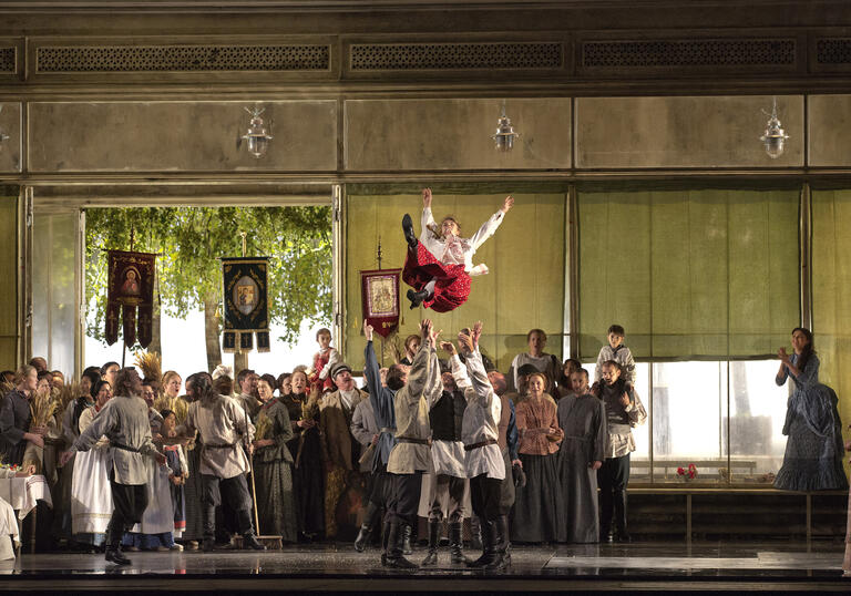 A woman in a red skirt is thrown into the air in this stage production of Eugene Onegin