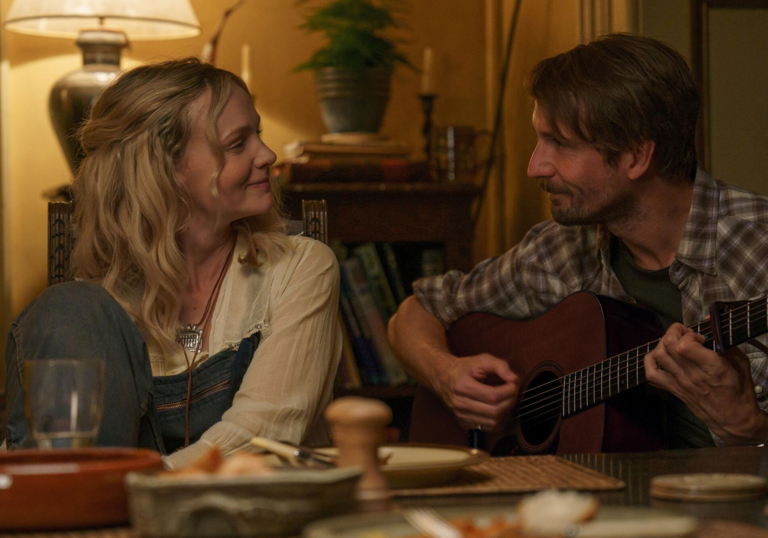 Carey Mulligan smiles at a man playing a guitar