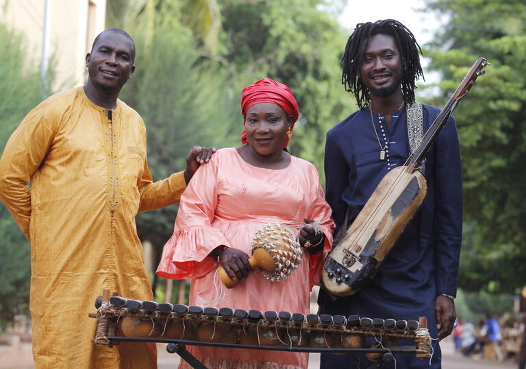 Trio Da Kali posing with their instruments with trees in the background