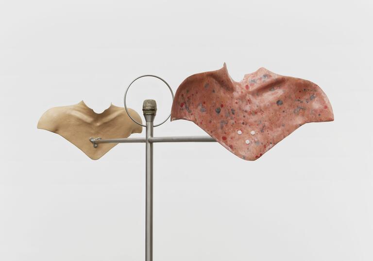 a sculpture shows ceramic moulds of human body parts lifted onto metal infrastructure