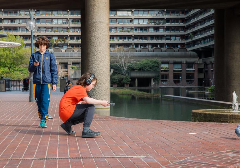 Two young children wear headphones and play with objects.