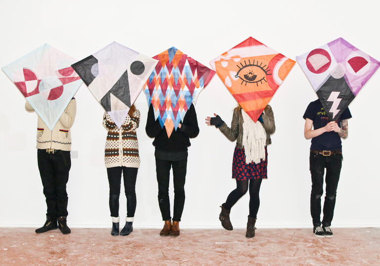 Five people stand in a line and pose with their kimono kite creations.