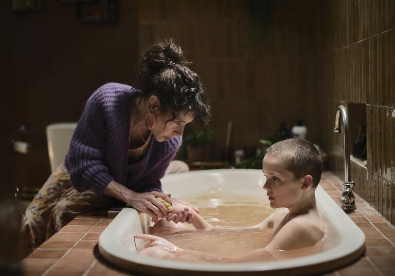 A woman and a child who is in a bathtub.