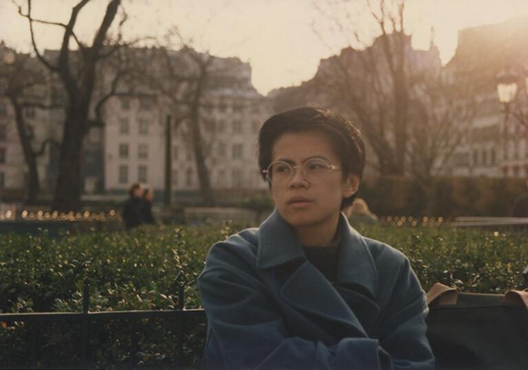 A woman sits on a bench in winter.