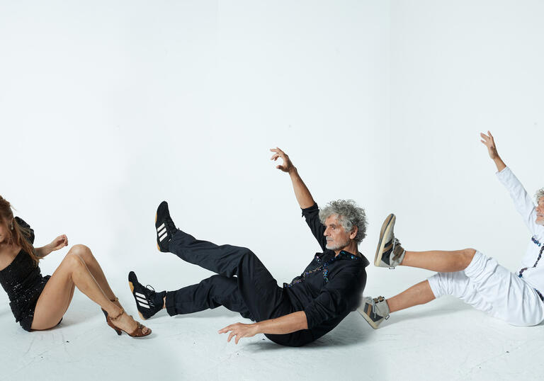 Kazu Makino and twin brothers Simone and Amedeo Pace are swept by an imaginary wind against a white background 