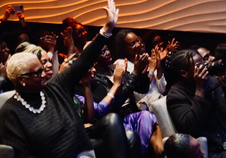An audience of people actively engaging and participating in an event by raising their hands