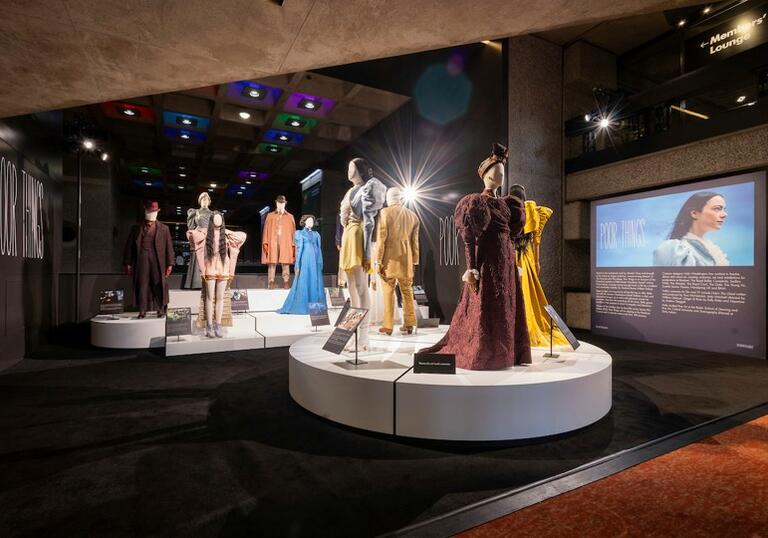 A photo of several costumes displayed on plinths, worn originally by the cast of the film Poor Things